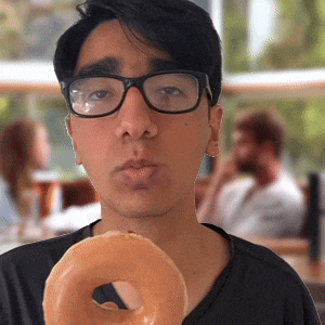 a young man wearing glasses is holding a donut in his hand