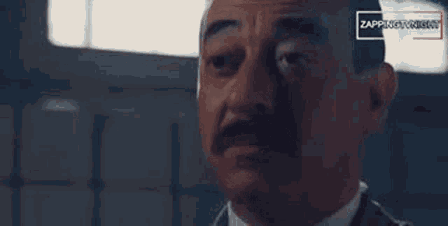 a man with a mustache is making a funny face .