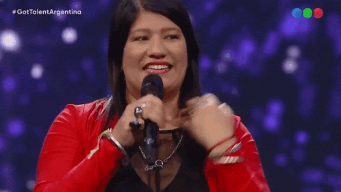 a woman in a red jacket is singing into a microphone with the hashtag gottalent argentina