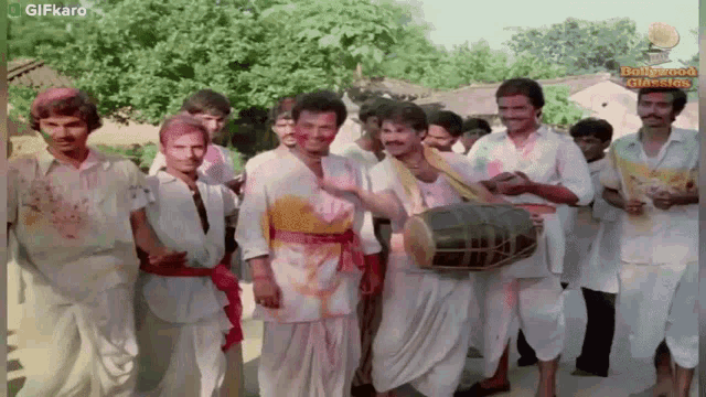 a group of men are playing a drum and smiling for the camera ..