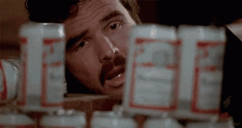 a man with a mustache is looking at budweiser cans .