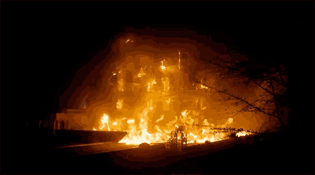a large building is on fire at night with flames coming out of it