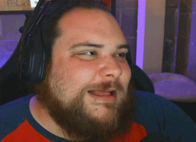a man with a beard is wearing headphones and laughing