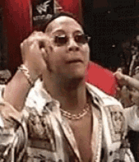 a man wearing sunglasses and a chain around his neck is adjusting his sunglasses .