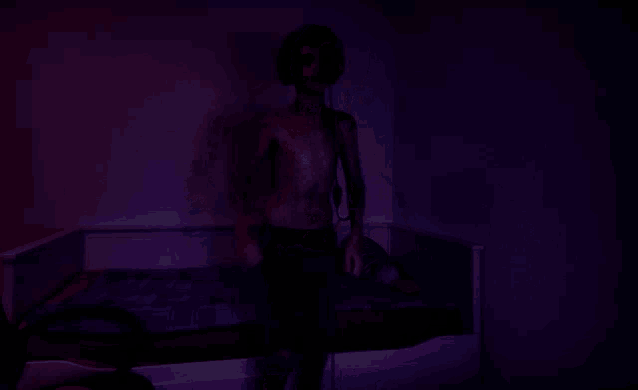 a man without a shirt is standing in a dark room with purple lights