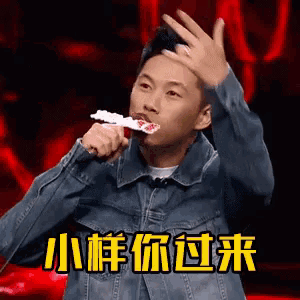 a man in a denim jacket is singing into a microphone while holding a piece of toothpaste in his mouth .