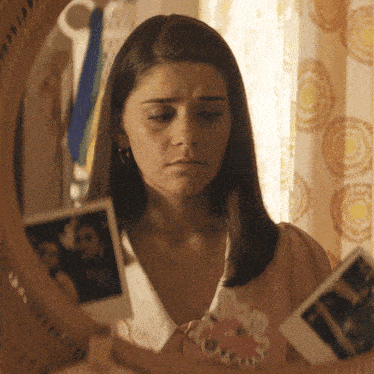 a woman looking at a picture of a man and woman in a mirror