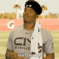 a football player wearing a headband and a towel around his neck is standing on a field .