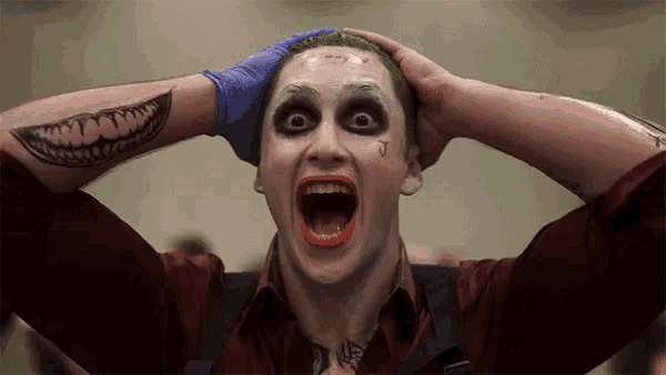 a man dressed as the joker is holding his head