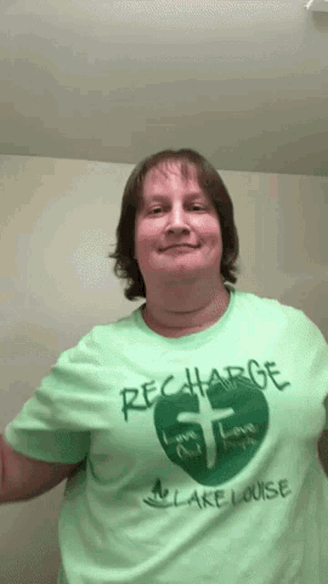 a woman is wearing a green recharge lake louise t-shirt
