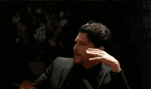 a man in a black suit and tie is laying down with his fist in the air
