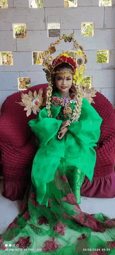 a little girl in a green dress is sitting on a chair