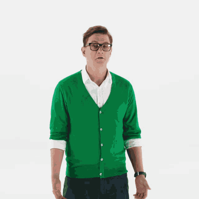 a man wearing glasses and a green cardigan is walking