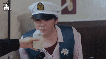 a man wearing a captain 's hat is drinking from a bottle
