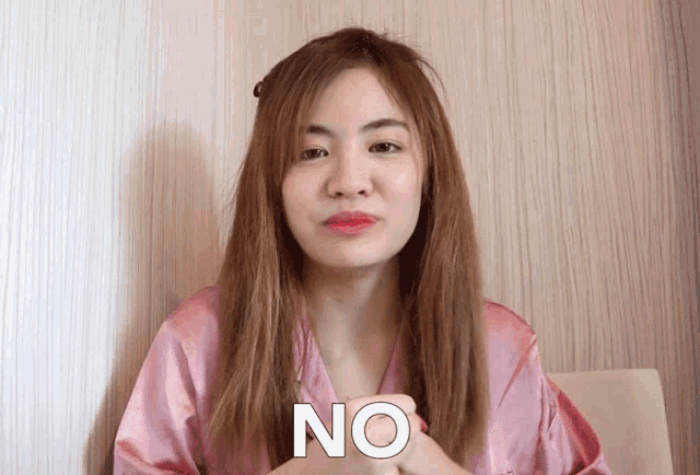 a woman in a pink robe says no with her hand