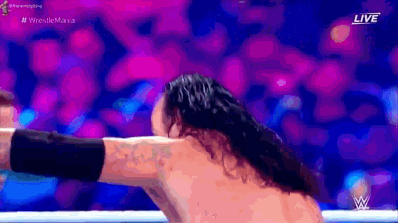 a man with long hair is standing in a ring with a purple background .