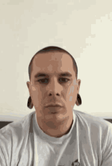 a man with ear plugs in his ears looks at the camera .