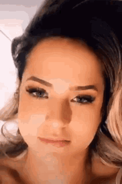 a close up of a woman 's face with long eyelashes and a serious look on her face .