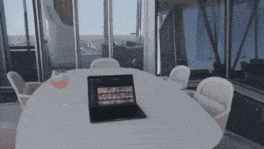 a laptop sits on a table with a glass of wine on it