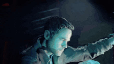 a man is standing in a dark room holding a gun in his hand .