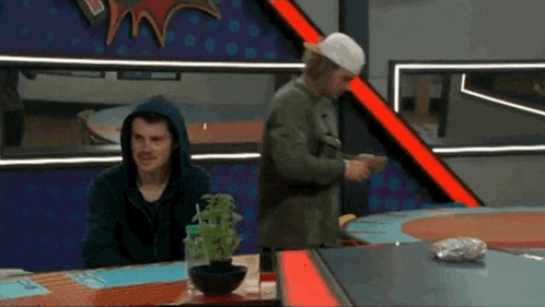 a man wearing a hooded jacket is standing next to another man