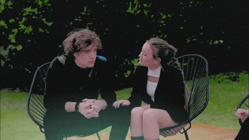 a man and a woman are sitting in chairs and talking