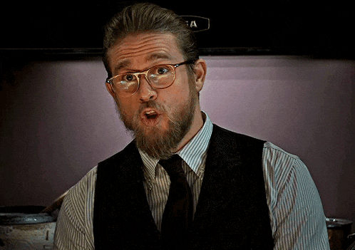 a man with a beard wearing glasses and a vest with a letter a on it