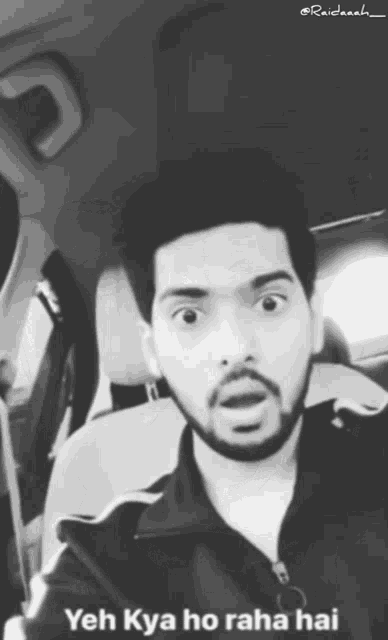 a black and white photo of a man in a car with yeh kya ho raha hai written on the bottom