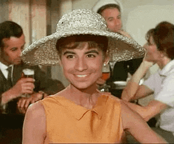 a woman wearing a straw hat and a yellow dress is smiling while sitting at a table .
