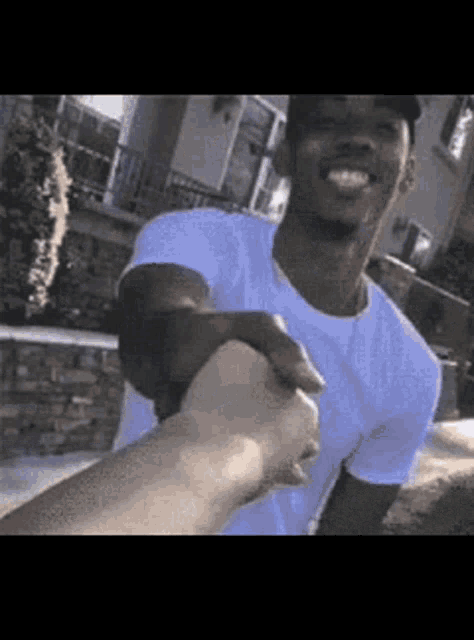 a man in a white shirt is holding another man 's hand and smiling .