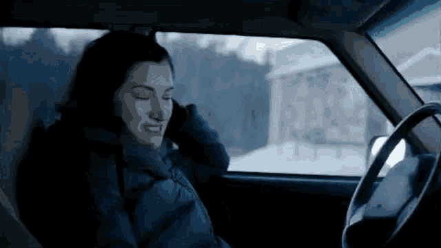 a woman is sitting in a car with her eyes closed