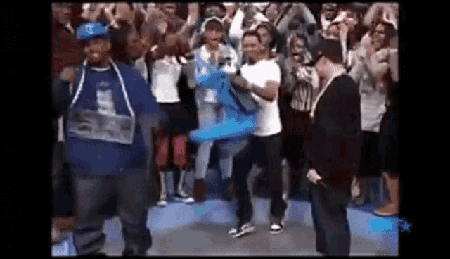 a group of people are dancing in front of a crowd while a man holds a blue balloon .