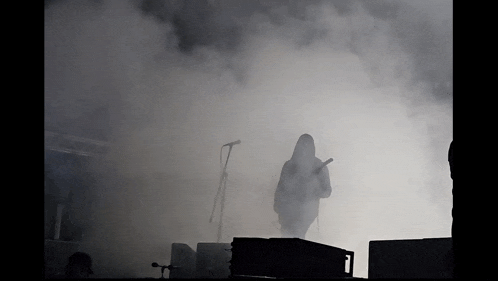 a silhouette of a person standing in a foggy room with a microphone