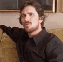 a man with a beard is sitting on a couch and making a funny face