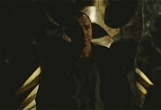 a man in a black jacket is sitting in a dark room looking down