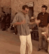 a man is dancing in a room with other people .