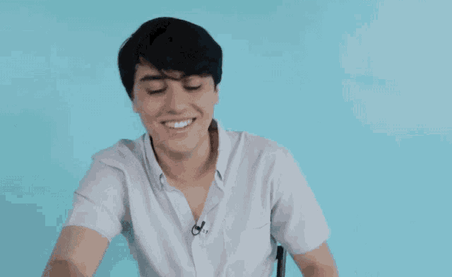 a young man wearing a white shirt with a microphone on his neck