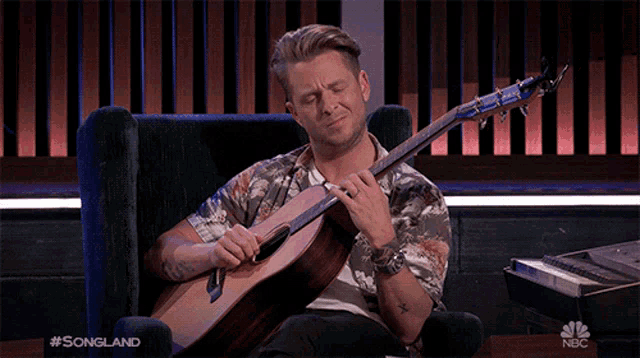 a man is sitting in a chair playing a guitar with the words #songland on the bottom