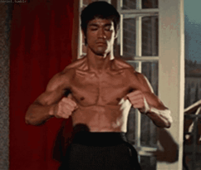 a man without a shirt is standing in front of a door .