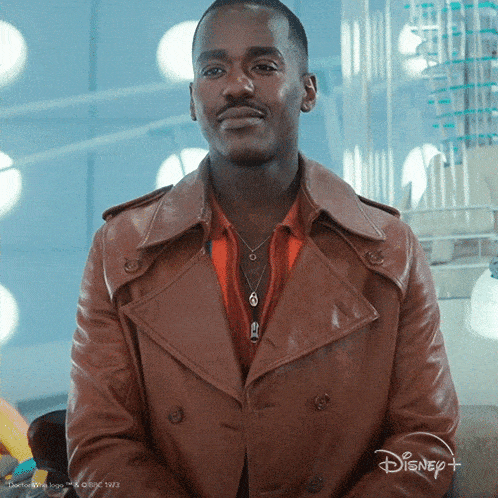 a man wearing a brown leather jacket is sitting in front of a disney+ logo