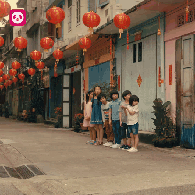 a group of children standing in front of a building with a panda logo in the corner