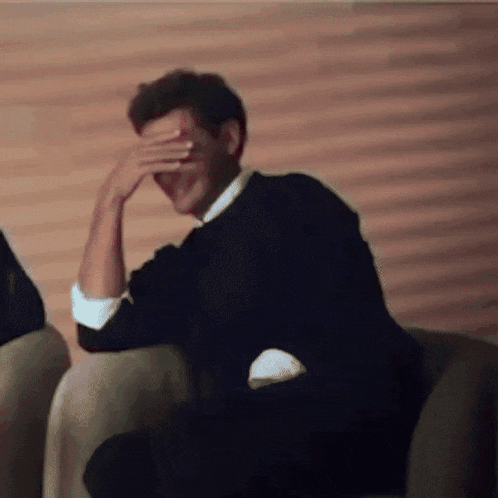 a man covering his face with his hand in a blurry photo