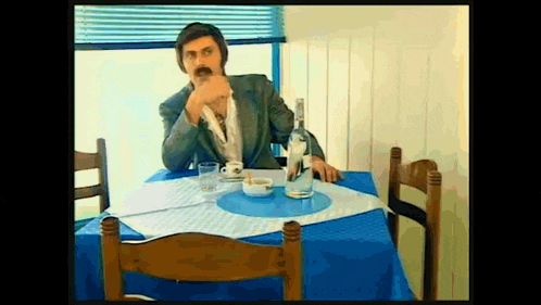a man is sitting at a table with a blue table cloth and a bottle of water