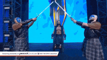 a man in a kilt is holding two lightsabers in front of two masked men .