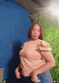 a woman is dancing in front of a green wall
