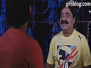 a man with a mustache wearing a yellow puma shirt