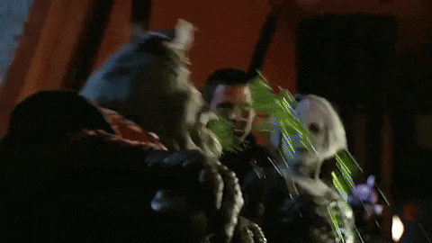 a man is standing next to a monster with green liquid coming out of its mouth .