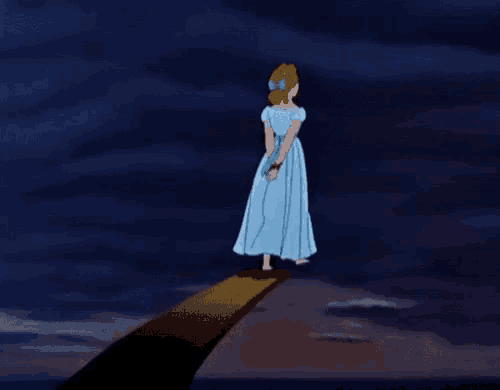 a woman in a blue dress is tied up on a ledge