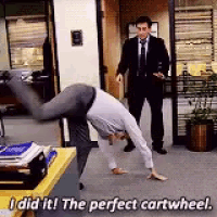 a man is doing a handstand in an office while a man in a suit watches .