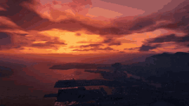 a sunset over a body of water with mountains in the distance